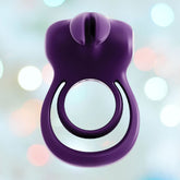Introducing the VeDO Thunder Bunny Vibrating Cock Ring, a vibrant purple silicone marvel from VeDO featuring an attached vibrating component. Set against a blurred, multicolored backdrop, its sleek design includes a loop and small top protrusion, making it an ideal choice for those seeking excitement with this innovative product.